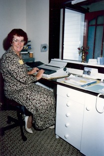 The very first Morrinsville Community House coordinator, Georgina  Thomas smiling up from her desk